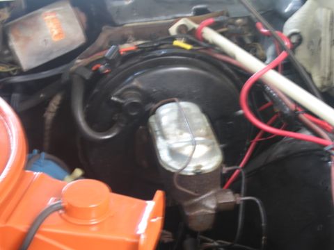 1991 Ford LTD Crown Victoria - classic car engine bay detail showing a black brake booster, chrome master cylinder, red battery cable and orange air cleaner edge.