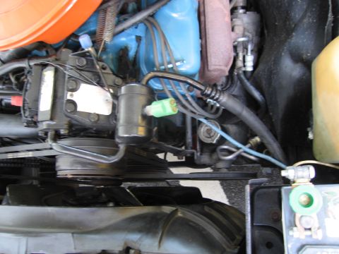 1991 Ford LTD Crown Victoria - Engine compartment detail showing a blue valve cover, alternator, belt and wiring beside an orange-painted firewall.