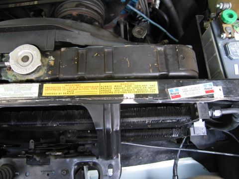 1991 Ford LTD Crown Victoria - Engine bay close-up of a radiator support showing yellow Chrysler antifreeze and Mopar warning decals.