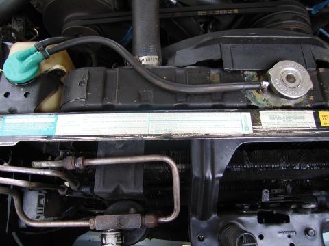 1991 Ford LTD Crown Victoria - Engine compartment detail with a green washer-fluid cap, radiator cap and instructional decals along the core support.