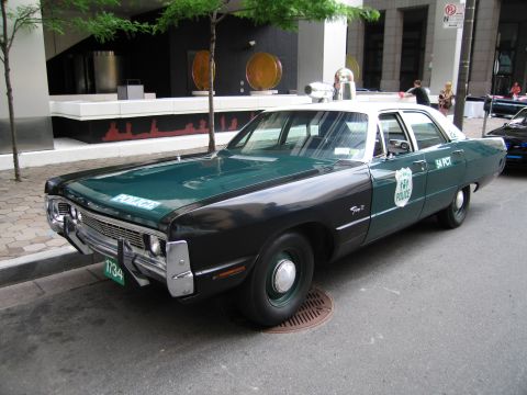 1991 Ford LTD Crown Victoria - green and white vintage NYPD 54 Precinct sedan with roof light parked curbside in a downtown street.