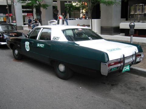 1991 Ford LTD Crown Victoria - Rear three-quarter view of a green and white vintage NYPD 54 Precinct sedan parked on a city street.