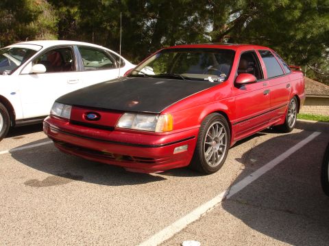 1993 Ford Taurus - 1993 Ford Taurus in a parking lot, showing its front three-quarter view with a contrasting black hood.