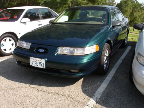 1993 Ford Taurus - Front view of a green 1993 Ford Taurus sedan, parked in a lot with another vehicle.