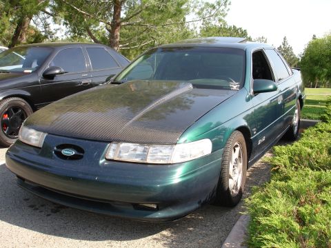 1993 Ford Taurus - A 1993 Ford Taurus is parked next to another car, with a carbon fiber hood modification.