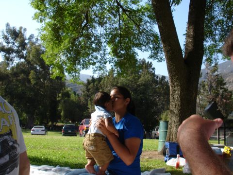 1993 Ford Taurus - A woman kisses a baby while sitting in a park, with several cars visible in the background.