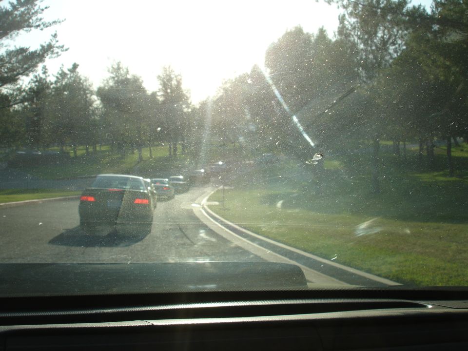 Rear view of a dark sedan in traffic, sun glare on windshield