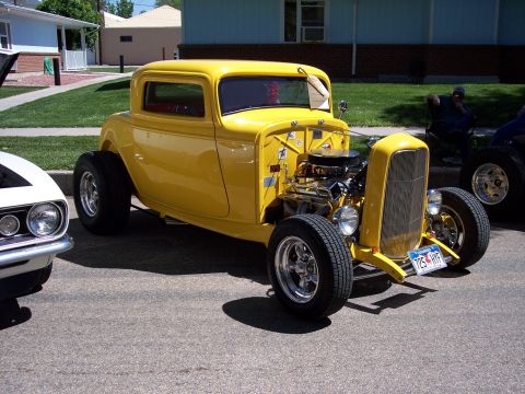 1972 Ford Ranchero - A bright yellow hot rod coupe is parked on a street, with another vehicle visible to its left.
