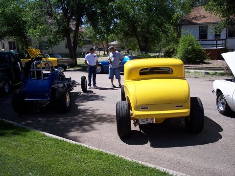 1972 Ford Ranchero - A bright yellow hot rod coupe is parked on the street, showing its rear end and custom license plate.