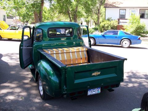 1972 Ford Ranchero - A classic green Chevrolet pickup truck is parked on a street with other vehicles visible in the background.