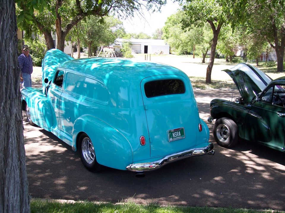 Turquoise panel van with chrome bumper and NSRA license plate, parked next to a green car