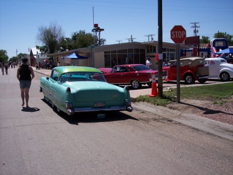1972 Ford Ranchero - A teal and green 1955 Chevrolet is parked on the street during a car show, with other classic vehicles visible.