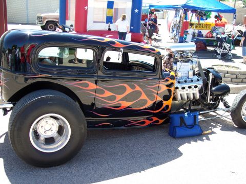 1972 Ford Ranchero - A custom hot rod with flame graphics and a prominent V8 engine is displayed at an outdoor car show.