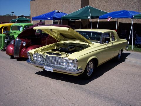 1972 Ford Ranchero - Yellow 1961 Plymouth coupe on display at a car show, with other vehicles in the background.