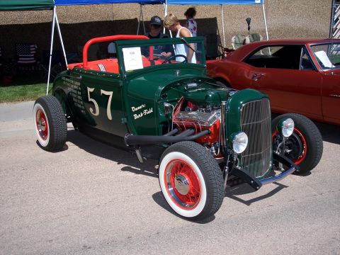 1972 Ford Ranchero - A green hot rod with a prominent number 57 on its side is displayed next to another vehicle under a tent.