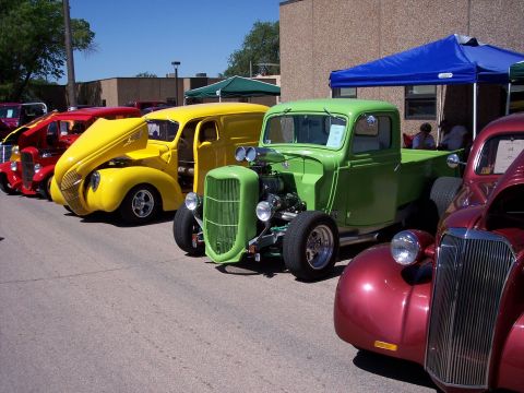 1972 Ford Ranchero - A line of custom hot rod vehicles are parked outdoors on a sunny day.