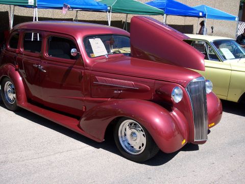 1972 Ford Ranchero - A maroon sedan with its hood open is displayed at a car show, with a yellow vehicle visible behind it.
