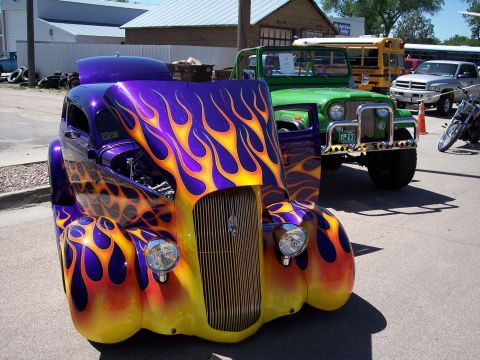 1972 Ford Ranchero - A custom purple hot rod with flame graphics is parked next to a green Jeep and a yellow school bus.