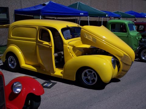 1972 Ford Ranchero - A yellow panel van is displayed at a car show with its hood and door open.
