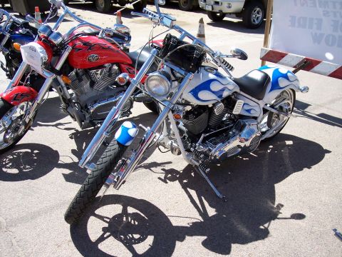 1972 Ford Ranchero - Custom motorcycles with flame paint jobs are parked on pavement, casting long shadows.