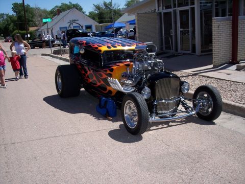1972 Ford Ranchero - A custom hot rod with a prominent supercharger and flame graphics is displayed at an outdoor car show.