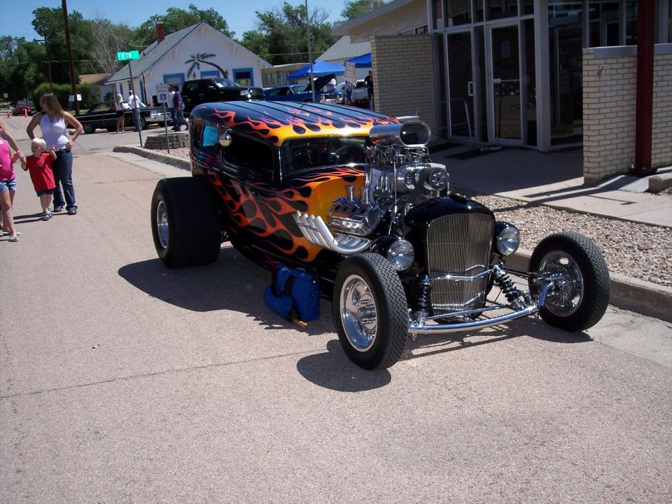 Black hot rod with flame paint, exposed engine, and chrome grille