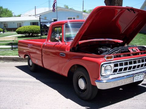 1972 Ford Ranchero - A red pickup truck, likely from the early 1960s, is parked with its hood open, revealing the engine compartment.