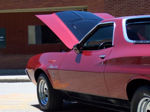1972 Ford Ranchero - A red 1972 Ford Ranchero is parked with its hood open, revealing black racing stripes.