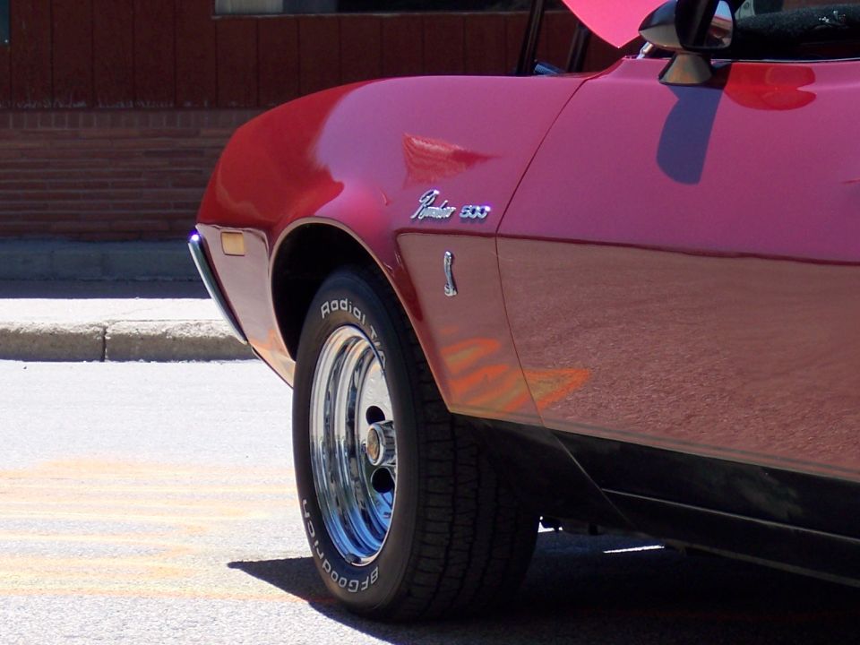Red 1970s Ford Ranchero 500 side view, showing front fender and wheel