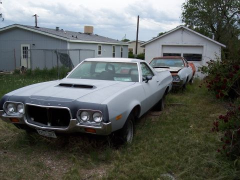 1972 Ford Ranchero - A light gray 1972 Ford Ranchero is parked in a grassy yard next to a garage, with another vehicle behind it.