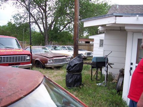 1972 Ford Ranchero - A collection of aging vehicles sits in a yard, with a barbecue grill nearby.