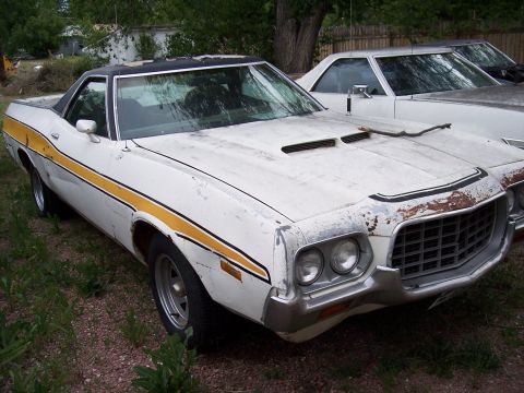 1972 Ford Ranchero - A weathered 1972 Ford Ranchero with a distinctive yellow stripe sits parked next to another vehicle.
