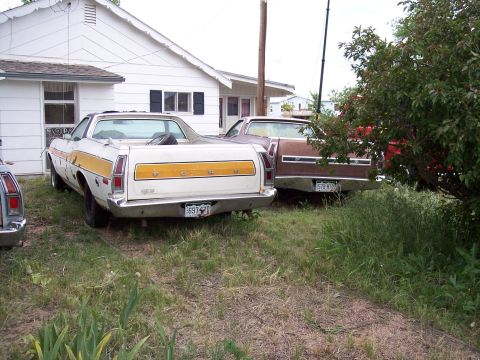 1972 Ford Ranchero - A white 1972 Ford Ranchero with a yellow stripe is parked in a yard next to another vehicle.