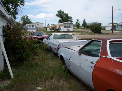 1972 Ford Ranchero - Two Ford Rancheros and a red car are parked in a grassy area with mobile homes in the background.