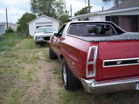 1972 Ford Ranchero - Rear view of a red 1972 Ford Ranchero parked on a gravel driveway next to a white car.