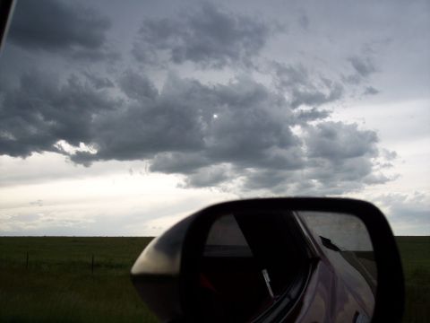 1972 Ford Ranchero - A reflection in a car's side mirror captures a dramatic sky with dark clouds and a sliver of sun over a rural landscape.