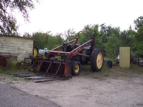 1972 Ford Ranchero - An old tractor with a front loader sits in a yard with a shed and trees in the background.