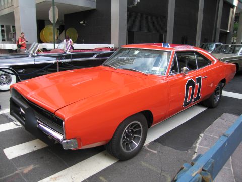 1991 Ford LTD Crown Victoria - orange Dodge Charger painted as the General Lee with '01' on the doors parked at an outdoor city car show.