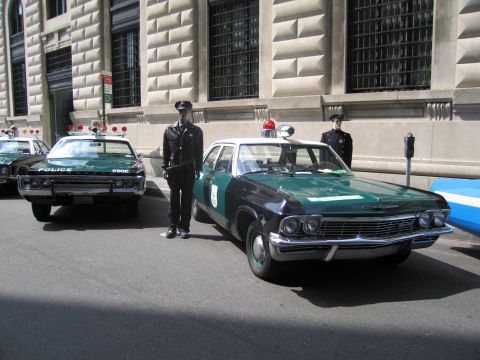 1991 Ford LTD Crown Victoria - Green and white vintage NYPD sedans parked along a building with uniformed officer mannequins standing alongside.