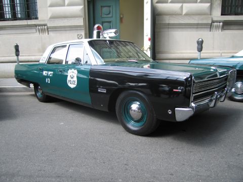 1991 Ford LTD Crown Victoria - green-and-white vintage POLICE sedan with a single roof beacon and door shield parked at a metered curb.