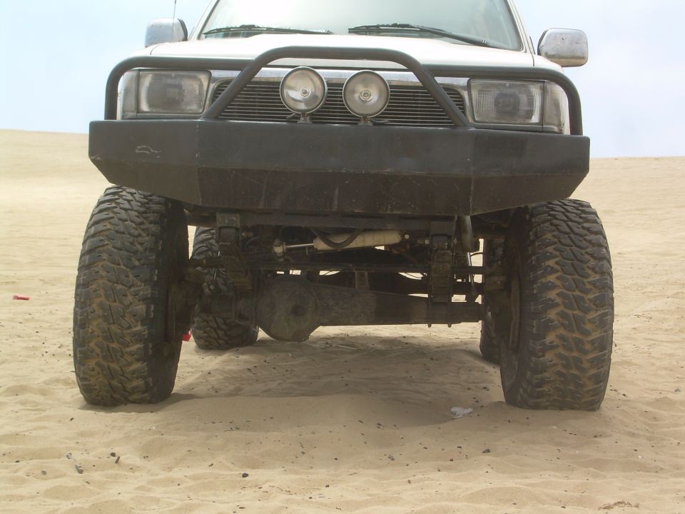 Lifted SUV front end on sand with off-road tires and light bar