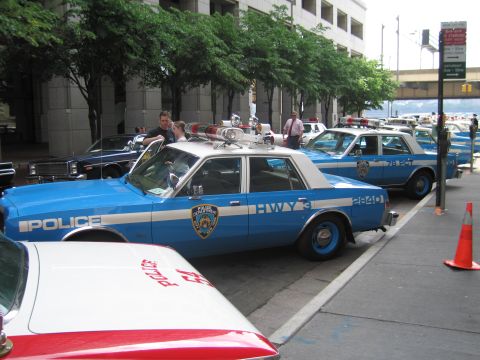 1991 Ford LTD Crown Victoria - vintage blue-and-white NYPD Highway Patrol sedan with rooftop lights sits curbside in a row of police cars on a city street.