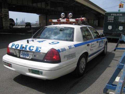 1991 Ford LTD Crown Victoria - Rear three-quarter of a white NYPD Highway Patrol Crown Victoria, unit 2849, with full rooftop lightbar, parked under a bridge.