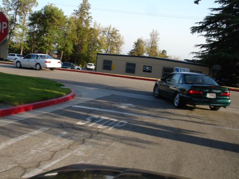 1993 Ford Taurus - A green sedan turns at an intersection with a stop sign, while a white car waits in the background.