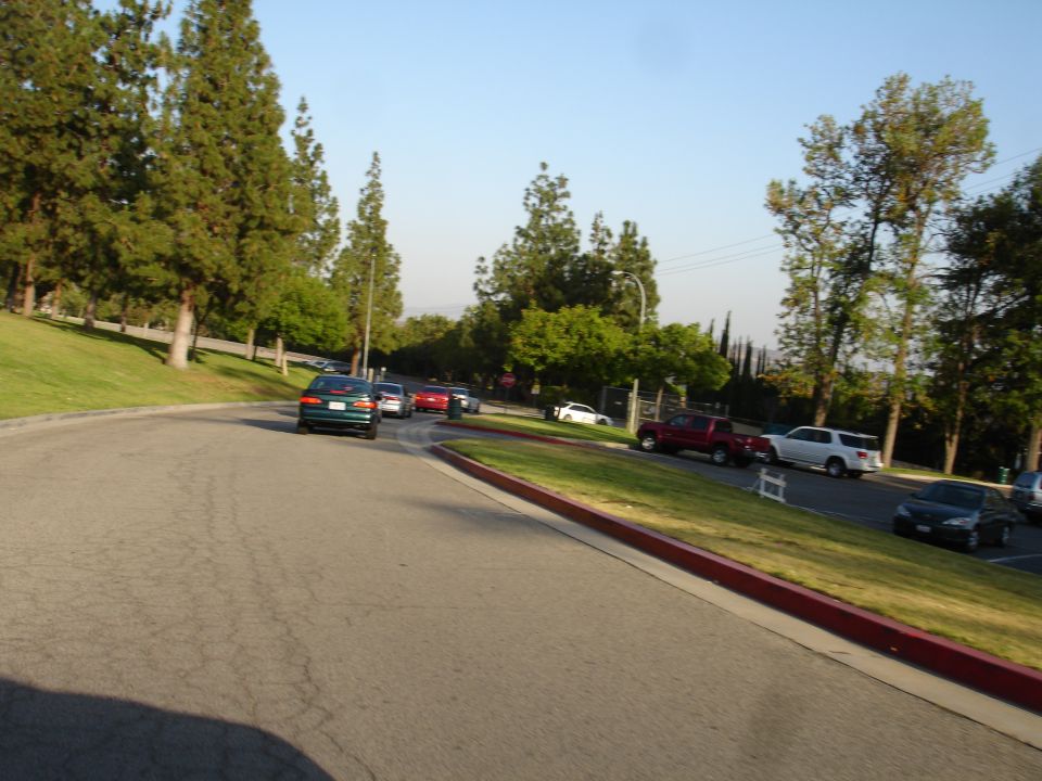 Green sedan driving on a road with other cars and trees