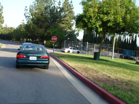 1993 Ford Taurus - A green sedan is parked on the side of the road near a stop sign.