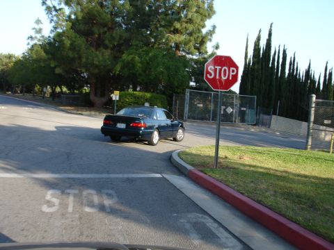 1993 Ford Taurus - Dark sedan turns at an intersection with a stop sign visible on the road and pole.