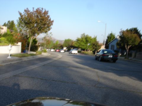 1993 Ford Taurus - A suburban street scene with multiple vehicles in motion and parked under a clear sky.