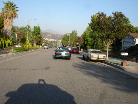 1993 Ford Taurus - A residential street with several cars parked along the curb under a clear sky.