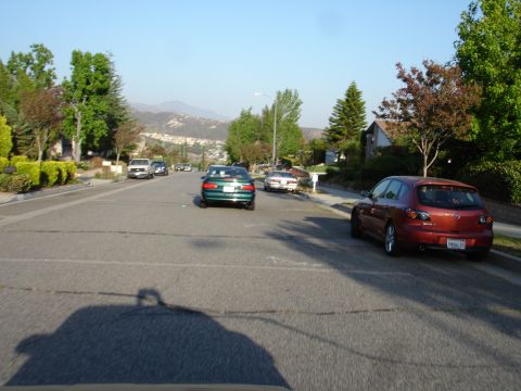 1993 Ford Taurus - Several cars are parked on a suburban street with hills in the background.